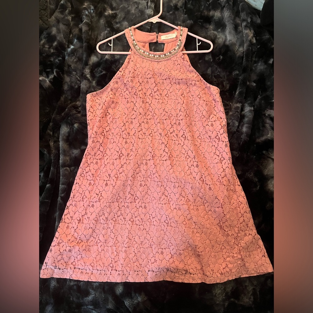 Pink sleeveless lace mini dress with jeweled collar and triangular cutout back.